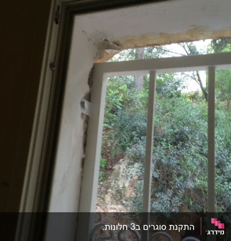 מסגרת חלון עם סורגי מתכת ונוף טבעי בחוץ